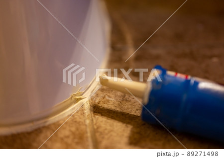 Selective focus on silicone caulking ready to be applied around the seal of a bathroom toilet. 89271498
