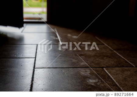 Track of small child footprints visible on a tile floor with an open door letting in light in the background 89271664