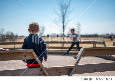 Child waiting along fence for next round of gaga ball in a school playground. Child waiting along fence for next round of gaga ball in a school playground. 89271673