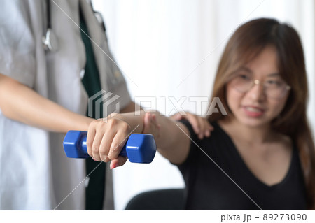 Young woman doing exercises under physiotherapist supervision. Physical therapy concept. 89273090