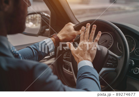 Unrecognized male pushing on the wheel of the automobile 89274677