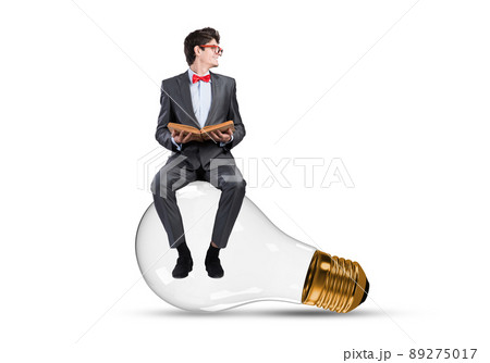 A young businessman sits on a light bulb A young businessman sits on a light bulb 89275017