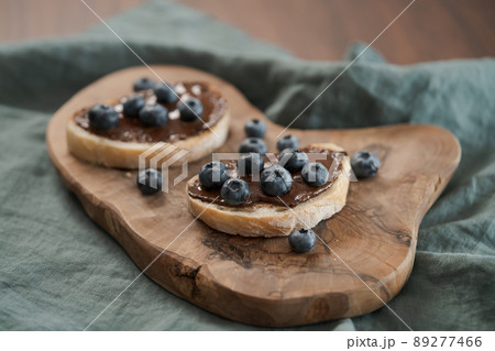 Organic chocolate hazelnut spread with fresh blueberries on ciabatta slices on wood board Organic chocolate hazelnut spread with fresh blueberries on ciabatta slices on wood board 89277466