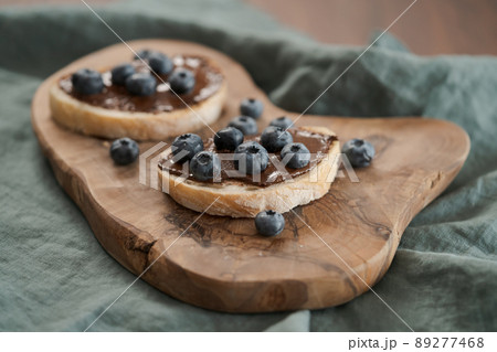 Organic chocolate hazelnut spread with fresh blueberries on ciabatta slices on wood board Organic chocolate hazelnut spread with fresh blueberries on ciabatta slices on wood board 89277468