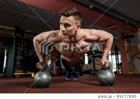 Man doing push-up exercise with dumbbell 89277690