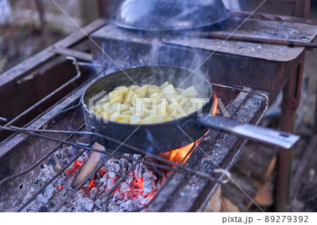 Fried potatoes on an open fire. The old frying pan is on the rack under the fire 89279392