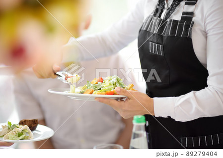 Waiter carrying plates with salad on some festive event, party or wedding reception. Staff of restaurant or cafe. Waiter carrying plates with salad on some festive event, party or wedding reception. Staff of restaurant or cafe. 89279404