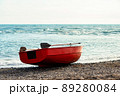 Small rowboat with sculls lying at shore of the sea 89280084