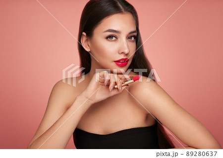 A beautiful young woman applying lipstick 89280637