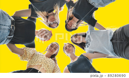 Happy girls friends hugging in a circle on a yellow background. Happy girls friends hugging in a circle on a yellow background. 89280690
