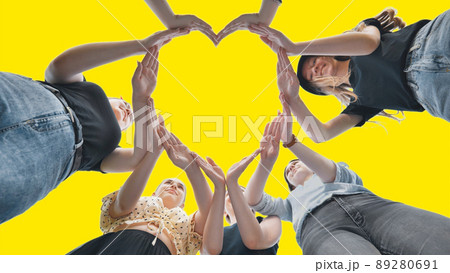 Girlfriends girls make a heart shape from their hands on a yellow background. 89280691