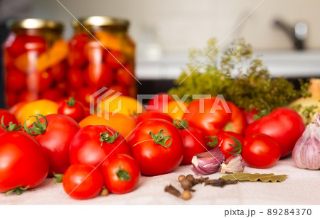 fresh red tomatoes, spices, seasonings and pickled tomatoes in jars on the table 89284370