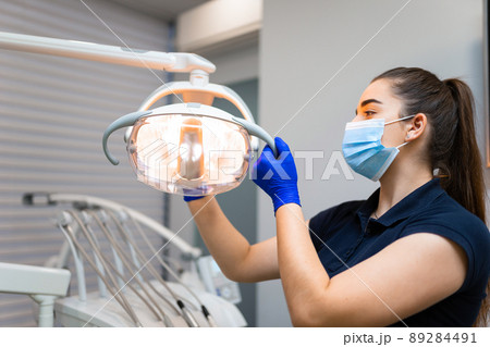 Dentist adjusts dental lamp to fit his needs Dentist adjusts dental lamp to fit his needs 89284491
