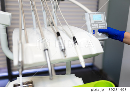 Dentist hand in glove press the control buttons of dental chair Dentist hand in glove press the control buttons of dental chair 89284493