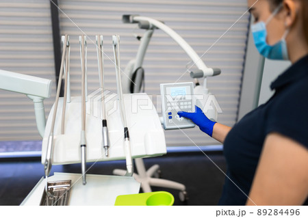 Dentist press the control buttons of dental chair 89284496