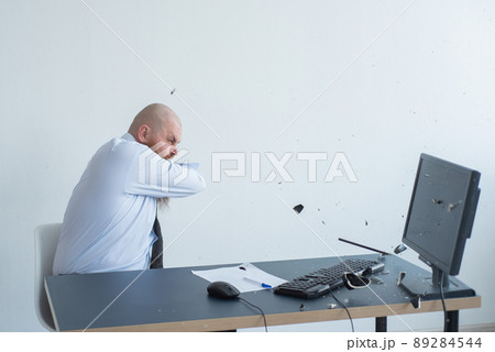 Angry bald man with a red beard in the office in a business suit crashes a computer. Manager with a nervous breakdown breaks the keyboard on the monitor. Angry bald man with a red beard in the office in a business suit crashes a computer. Manager with a nervous breakdown breaks the keyboard on the monitor. 89284544