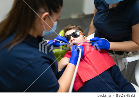 Dentist and assistant make preventive dental plaque cleaning for teenager 89284932