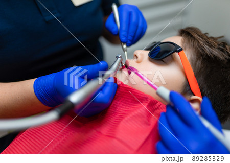 Dentist and assistant make preventive dental plaque cleaning for teenager 89285329
