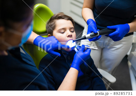 Dentist and assistant treats teeth to teenager.  89285731