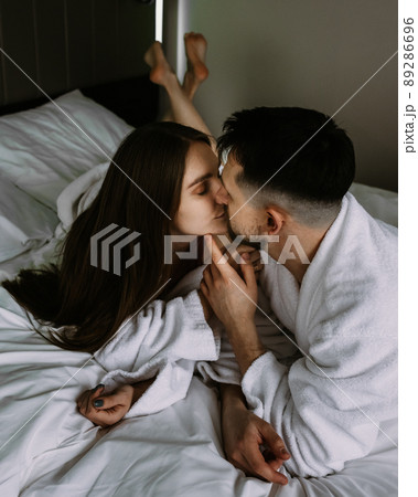 Young loving couple kissing on bed at hotel Young loving couple kissing on bed at hotel 89286696