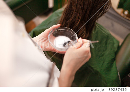 Hairdresser applies a hair mask to the woman in the beauty salon. Botox and keratin hair straightening procedure. Hairdresser applies a hair mask to the woman in the beauty salon. Botox and keratin hair straightening procedure. 89287436
