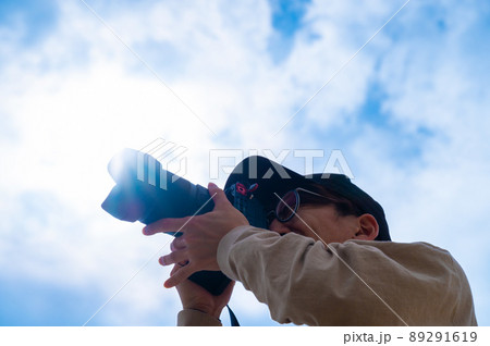 青空の下、一眼レフカメラで楽しく撮影する若い男性 89291619
