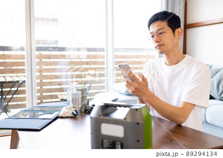 ポータブル電源を使ってスマホを充電しながら情報収集をしている男性 ポータブル電源を使ってスマホを充電しながら情報収集をしている男性 89294134