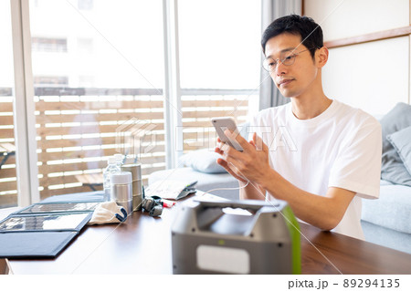 ポータブル電源を使ってスマホを充電しながら情報収集をしている男性 ポータブル電源を使ってスマホを充電しながら情報収集をしている男性 89294135