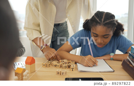 African American female teacher standing with pupils teaching writing lesson in modern classroom. African American female teacher standing with pupils teaching writing lesson in modern classroom. 89297822