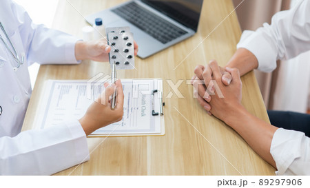 Visiting a doctor concept A physician suggesting his patient to take capsule for treatment and explaining how to take them. 89297906