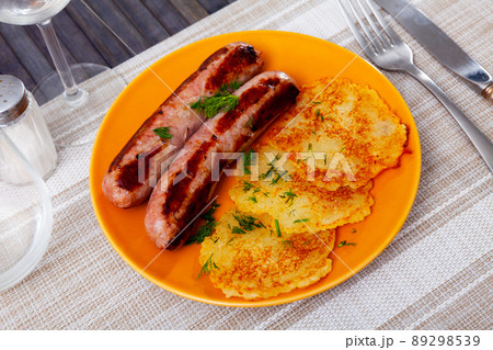 Ukrainian deruny, potato flapjacks, with fried sausages on plate 89298539
