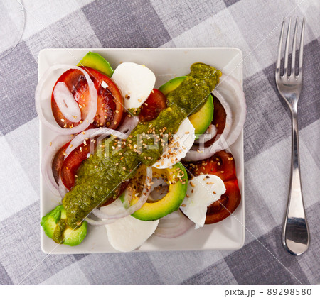 Salad of mozzarella, tomatoes, onion and avocado with pesto and sesame Salad of mozzarella, tomatoes, onion and avocado with pesto and sesame 89298580