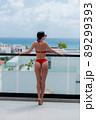 Summer holidays in luxury hotel, woman relaxing near beautiful rooftop swimming pool. Sexy girl wearink bikini enjoy ocean view. Back view, without face 89299393
