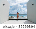 Happy woman beside a rooftop pool with a beautiful city and ocean view on background 89299394