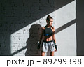Beautiful contrasting portrait with the play of light and shadow of a young and fit girl in a loft interior with a white brick wall 89299398