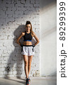 A young female athlete with a perfect body and abs is preparing for training in the early morning 89299399
