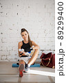Female fighter exhausted after exercise feeling dehydration, drinks isotonic drink from bottle. Young woman rest after intense training in a boxing studio. 89299400
