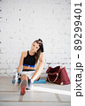 A young girl got tired during boxing training and sat down against the wall to rest and drink 89299401