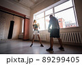 Female boxer practicing hits with her personal trainer in a boxing studio. 89299405