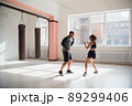 An attractive young boxer teaches his girlfriend boxing techniques in a loft equipped for boxing training 89299406