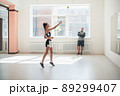 A young girl performs a coach's task for coordination and quick reaction under the guidance of her coach 89299407