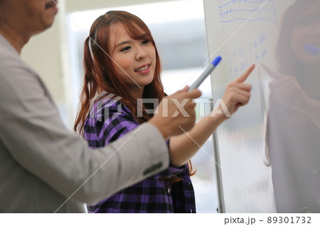 Tutor with cheerful young woman student teaching sound phonetic note on white board. 89301732