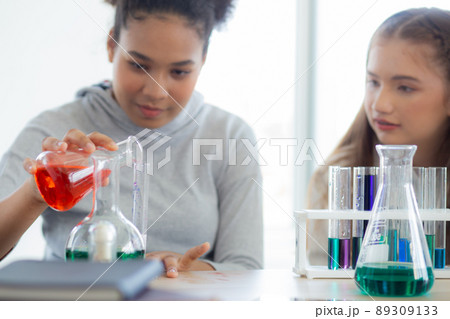 Young teacher teaching group student about science and test chemical for liquid in the lab of school 89309133