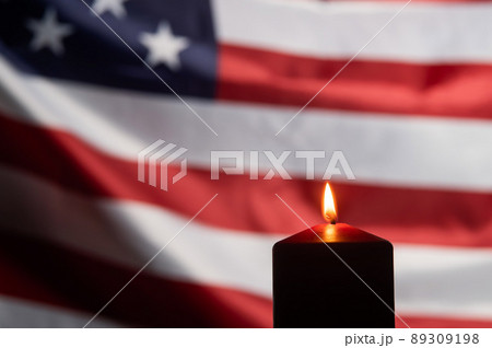 Burning candle against the background of the waving flag of the united states of america in the dark. Burning candle against the background of the waving flag of the united states of america in the dark. 89309198