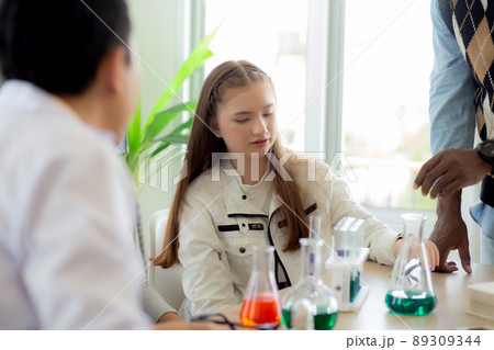 Young teacher teaching group student about science and test chemical for liquid in the lab of school 89309344