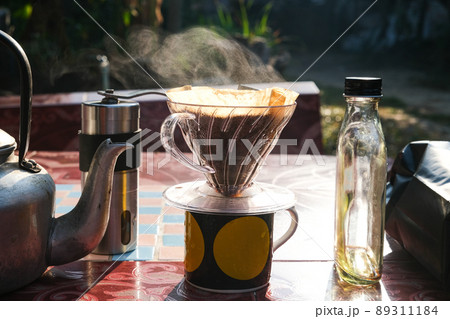 Drip brewing coffee by paper filtered on table morning outdoor Drip brewing coffee by paper filtered on table morning outdoor 89311184