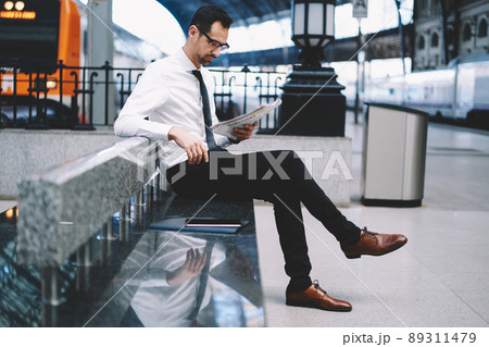 Side view of confident businessman in spectacles for eyes protection reading finance newspaper Side view of confident businessman in spectacles for eyes protection reading finance newspaper 89311479