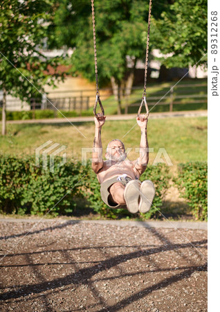 A mature gray-haired man exercising in the park 89312268