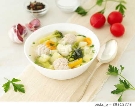 bowl of soup, a cup of broth and vegetables, meatballs made of turkey and chicken, side view bowl of soup, a cup of broth and vegetables, meatballs made of turkey and chicken, side view 89315778