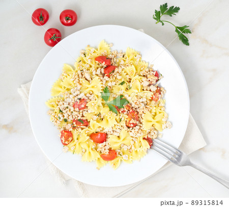 farfalle pasta with tomatoes, chiken meat, parsley on white stone background, low-calorie diet, top view farfalle pasta with tomatoes, chiken meat, parsley on white stone background, low-calorie diet, top view 89315814